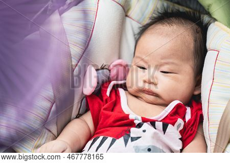 Portrait Asian Baby Boy Is Sleepy, Toddler Is Reclining In Car Seat. Blurry Purple Fan Power Is Ligh