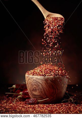 Chilli Flakes Are Poured Into A Wooden Dish. Chilli Flakes And Dried Chili Peppers On A Brown Backgr