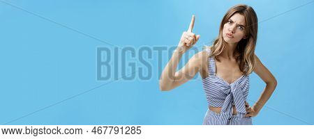 Strict Serious-looking Young Mother Giving Directions Raising Index Finger And Frowning To Look Scar