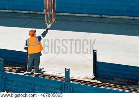 Slinger In Helmet And Vest Unloads Metal Pipes And Fittings From Truck Body On Clear Day.. Productio