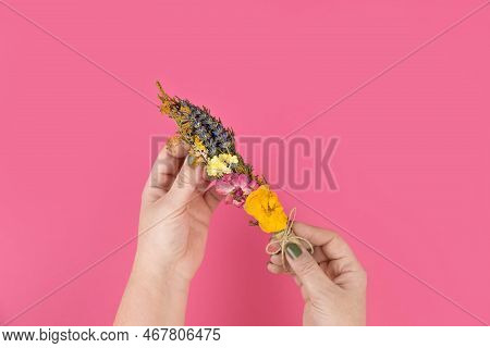 Womens Hands Holding A Smudge Stick To Banish Bad Energy. Dried Herbs And Flowers Are Tied Into A Bu