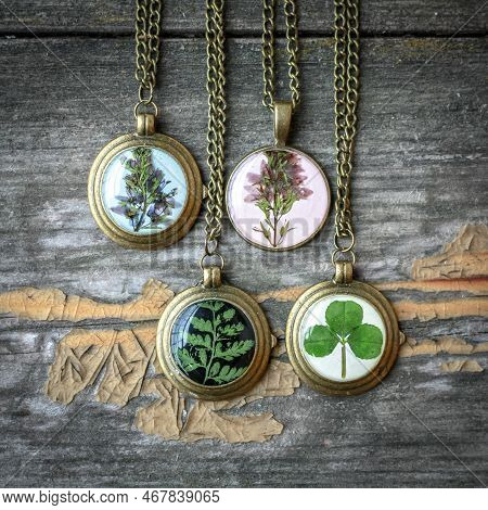 Close Up Pendants With Wildflowers And Leaves Concept Photo. Craft Jewelry. Top View Photography Wit