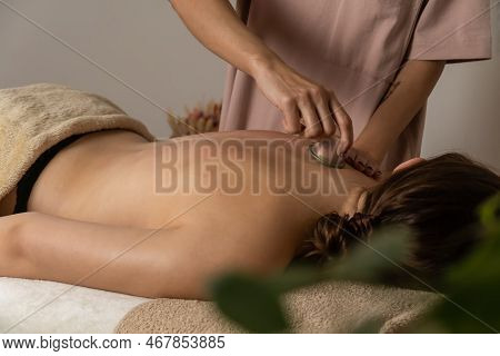 Massage Therapist In A Spa Salon Does A Massage With A Vacuum Jar On His Client's Back For A Healing