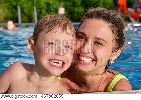 Caring Young Mother Teaches Her Son To Swim In A Pool With Clear Water On Vacation. Happy Child Spla