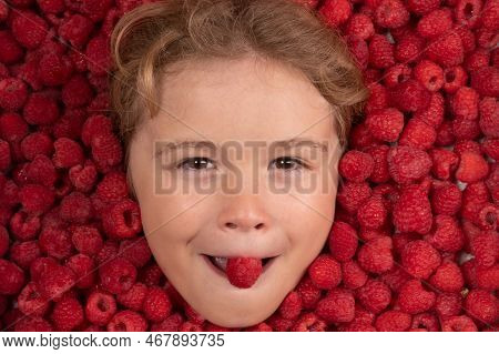 Funny Kids Face Near Raspberry Background. Raspberry In Kids Mouth. The Kids Face With Raspberries F