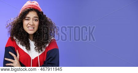 Woman With Curly Hair In Winter Beanie Feeling Uncomfortable And Discomfort Clenching Teeth And Frow