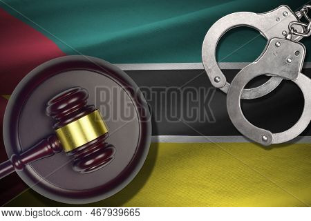 Mozambique Flag With Judge Mallet And Handcuffs In Dark Room. Concept Of Criminal And Punishment, Ba