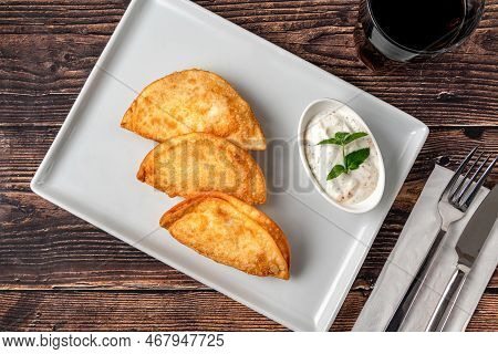 Beef Cheburek On A Wooden Table. Deep Fried Beef Dumplings With Meat And Onions. Turkish Name Ci Bor