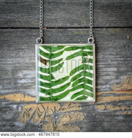 Close Up Square Pendant With Fern Leaves Concept Photo. Floral Bijouterie. Top View Photography With
