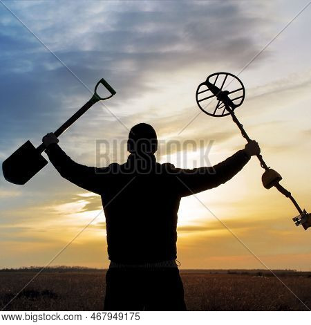 A Happy Treasure Hunter With A Metal Detector On The Background Of A Beautiful Sunset
