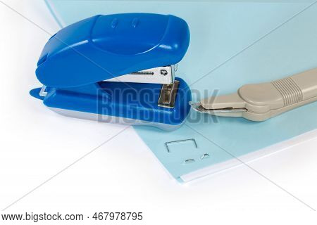 Small Manual Paper Stapler And Simple Pen Type Staple Remover On Stapled Paper Sheets On A White Bac