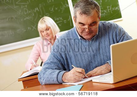 교실에서 서 면된 작업을 수행 하는 안경에 수석 남자