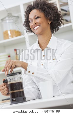 Una ragazza afro-americana bella felice di razza mista o una giovane donna che fa il caffè con una caffettiera in 