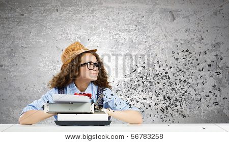 Young funny woman in glasses using typewriter