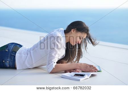 beautiful young woman relax and work on laptop computer while listening music on heaphones and read book at home