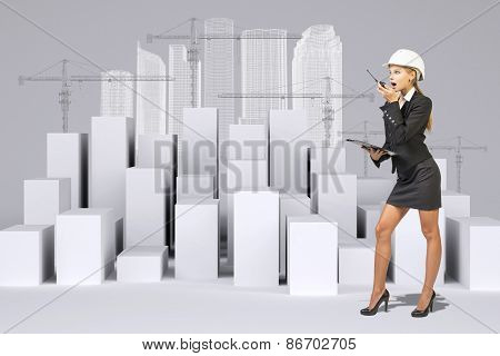 Business woman using walkie-talkie. Many white cubes with wire-frame buildings
