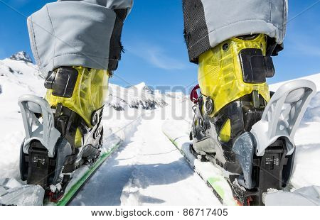 Close Up Of Skier's Boots And Skis From Ground Level.