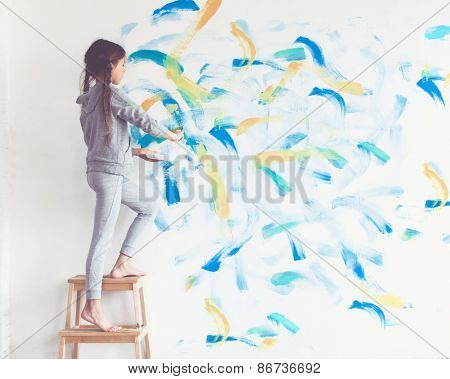 8 years old girl painting the wall at home, Instagram style toning