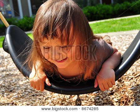 Cute mixed toddler girl playing a small swing