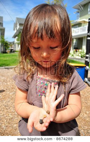 Cute mixed toddler girl playing with stones in her hands