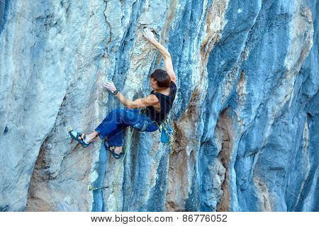 Rock climber climbing up a cliff