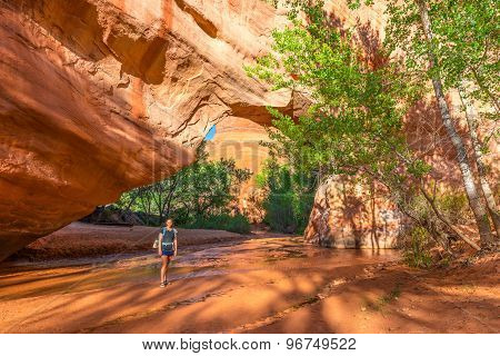 Girl Backpacker Walking Under Natural Bridge Arch Coyote Gulch