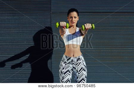 Sporty woman holding weights with hands up at her front getting arms in great shape