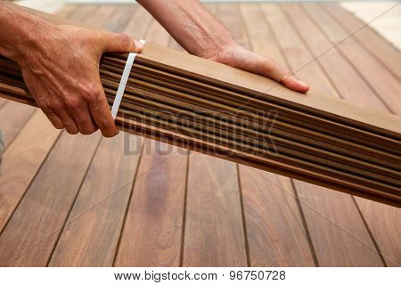 Ipe decking installation with carpenter hands holding tropical wood slats