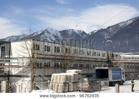 GARMISCH PARTENKIRCHEN, GERMANY. Feb 01 2011: Paraglider pilots fly over the construction site of the offices for the TV and organisers preview images for the 2011 Alpine skiing World Championships