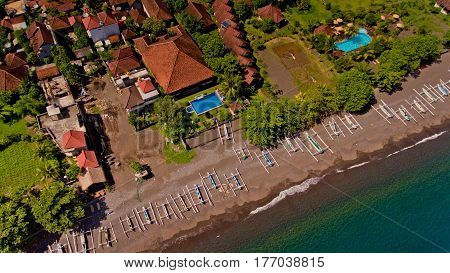 The tropical bay with stony beach boats and buildings aerial view. Village of Amed Bali Indonesia.