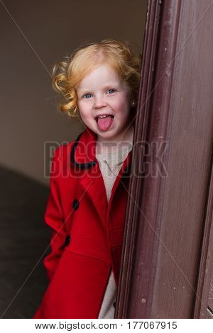 Portrait Of A Beautiful Little Girl With Red Hair In A Red Coat