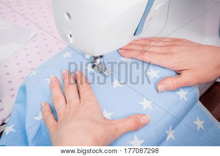 Woman's hands with dress at sewing machine close up