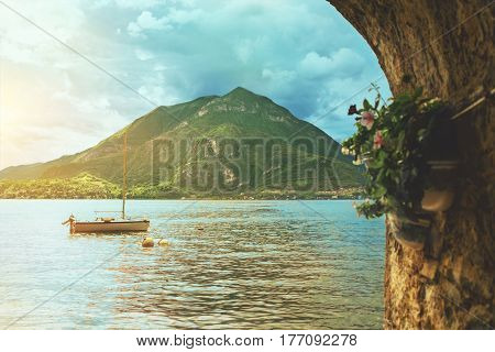 Beautiful colorful panoramic view of waterscape of Como lake coastline with a boat mountain and cloudy sky