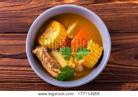 Puchero Soup With Corn And Parsley On Wooden Table