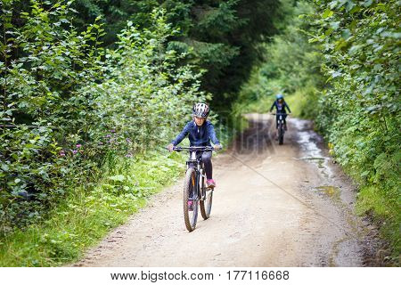 Teenage girl in helmet riding the bicycle on mountain road