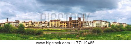 Beautiful panoramic view of Flornce Arno River National Library in the middle green riverside and majestic powerful clouds.