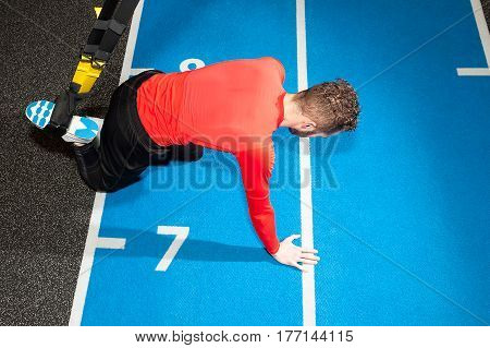 young sporty bearded man prepares for exersising in gym select the length of the sling straps