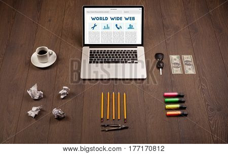 Laptop computer on wooden desk with office suplies