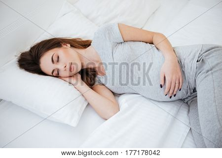 Side view of sleeping pregnant woman on bed in home