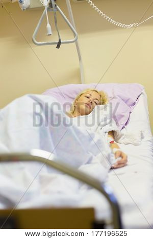 Bedridden female patient lying in hospital bed, recovering after surgery.
