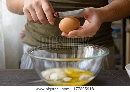 Close-up of woman's hands breaking egg during cooking