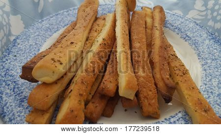 Breadsticks with different spices in a blue plate
