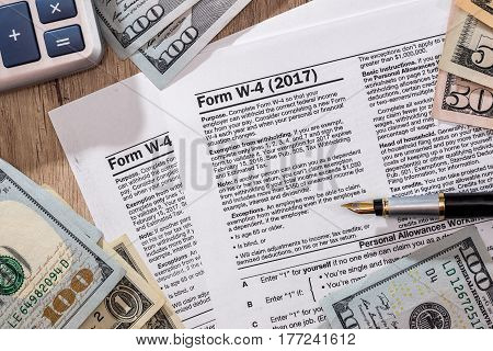W4 Tax Form With Money, Pen And Calculator On Desk.