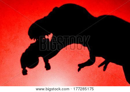 shadow of tyrannosaurus biting a body on wall in red close up no logo or trademark