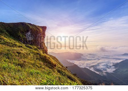 Beautiful landscape nature of sunrise on peak mountain with sun cloud fog and bright colors of sky in winter at Phu Chi Fa Forest Park is a famous tourist attraction of Chiang Rai Province Thailand