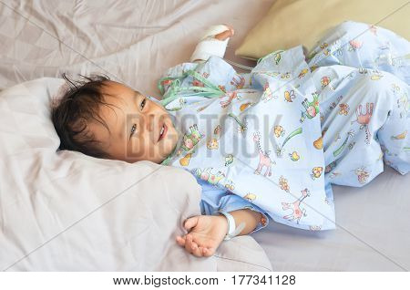 Little boy looking his parent in bed in hospital room. Child with IV tube. recovering from sickness.