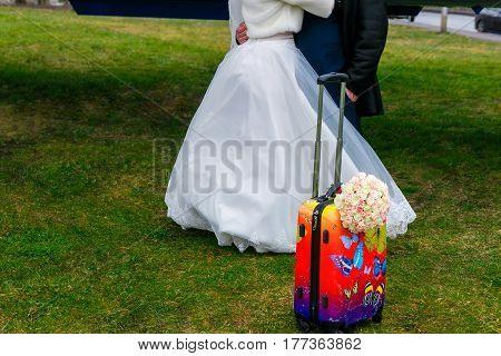 Unrecognizable Wedding Pair With Suitcase And Bridal Bouquet. Honeymoon Trip.