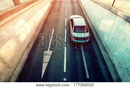 Aerial view of white car exiting underground garage vehicle on the road in underpassage