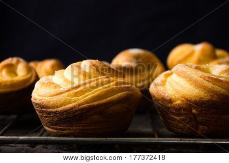 Cruffin - Buns from yeast dough. Dark graunge background. Mystical light. cinnamon craffin (cinnabon) (mix of croissant and muffin)