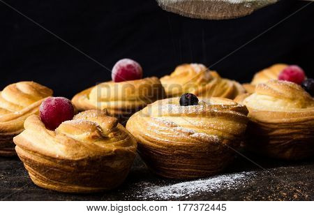 Cruffin - Buns from yeast dough. Dark graunge background. Mystical light. cinnamon craffin (cinnabon) (mix of croissant and muffin)